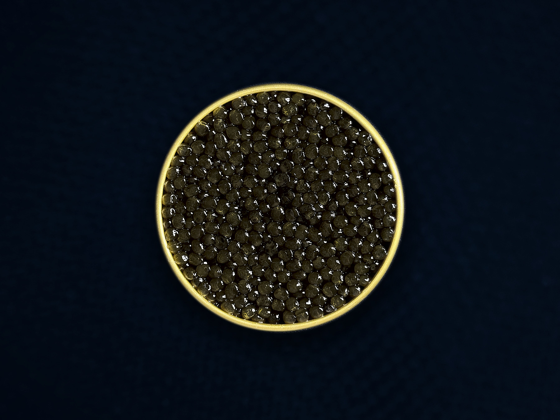 An open gold tin of AMANO caviar on midnight-blue textile — editorial presentation; natural batches vary